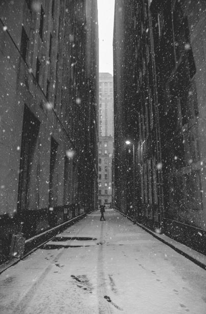 A person standing between two buildings in the snow